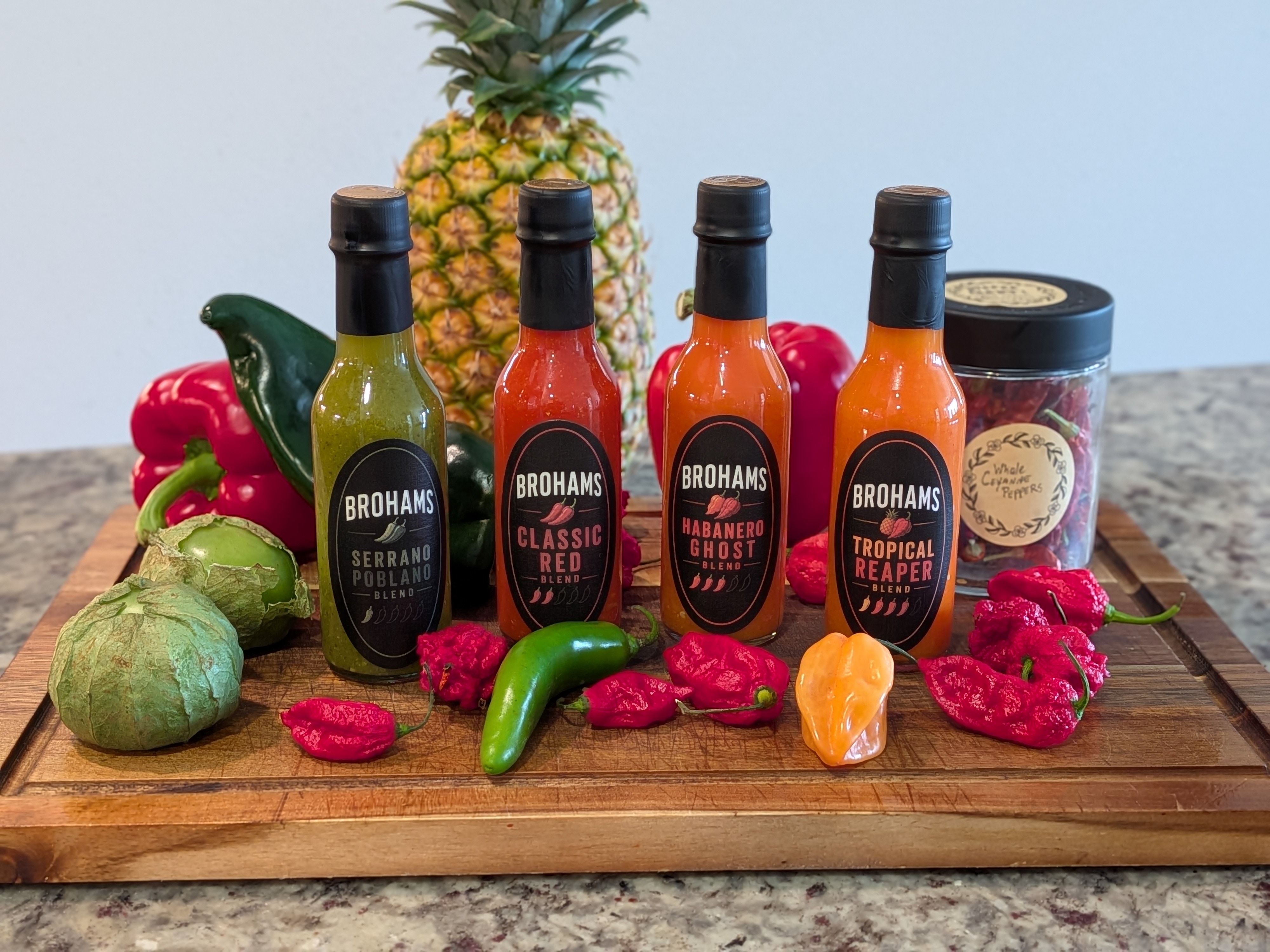 Brohams Sauce full lineup on a wooden cutting board surrounded by fresh peppers